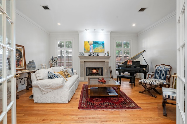 living room featuring light wood-type flooring, a wealth of natural light, and crown molding