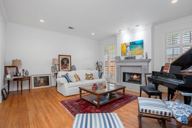 living room featuring light wood-type flooring, a healthy amount of sunlight, and ornamental molding