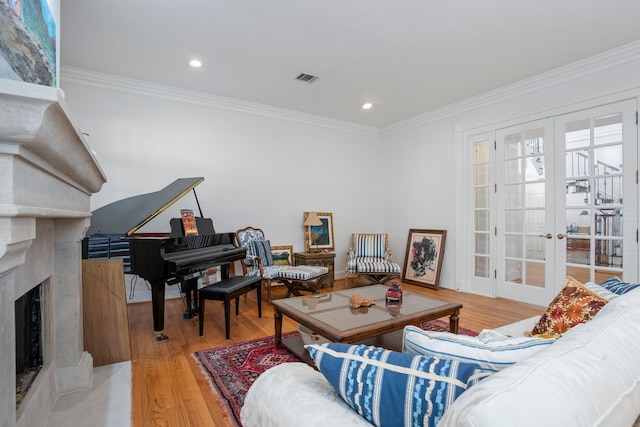 living room featuring a high end fireplace, ornamental molding, french doors, and light wood-type flooring