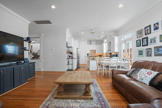 living room featuring ornamental molding, ceiling fan, and light hardwood / wood-style flooring