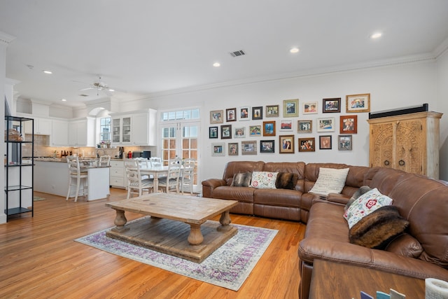 living room featuring light hardwood / wood-style floors, crown molding, and ceiling fan