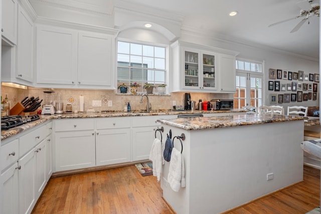 kitchen featuring white cabinets, stainless steel gas cooktop, decorative backsplash, and sink