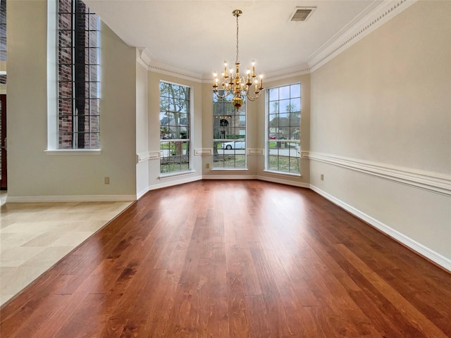 unfurnished dining area featuring hardwood / wood-style floors, an inviting chandelier, and ornamental molding