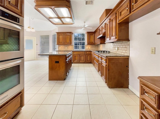 kitchen with dark stone countertops, a center island, light tile patterned floors, and appliances with stainless steel finishes