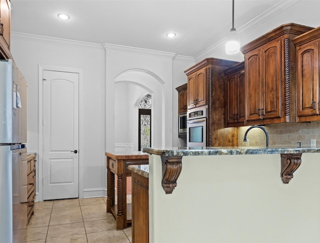 kitchen featuring crown molding, light stone countertops, and appliances with stainless steel finishes