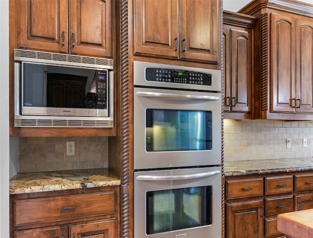 kitchen with decorative backsplash, light stone countertops, and appliances with stainless steel finishes