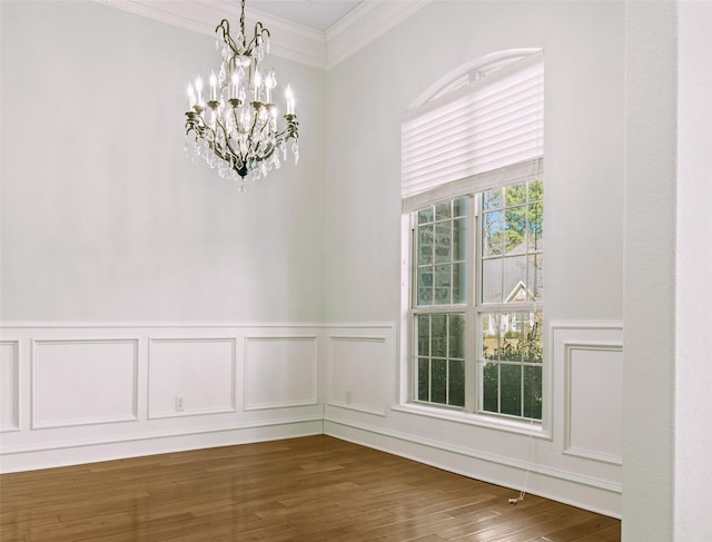 spare room featuring an inviting chandelier, dark hardwood / wood-style flooring, and crown molding