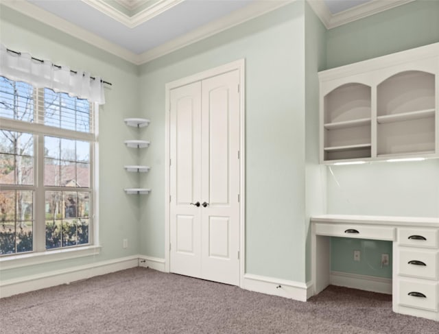 unfurnished office featuring built in desk, carpet, and ornamental molding