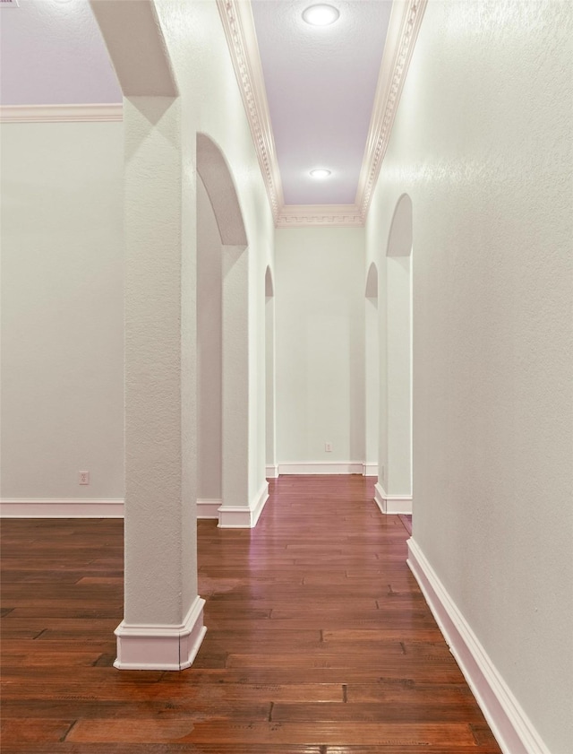 corridor with dark wood-type flooring and crown molding