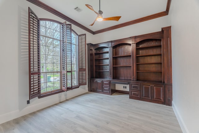 unfurnished office featuring crown molding, a wealth of natural light, built in desk, and light hardwood / wood-style floors