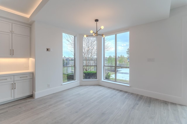 unfurnished dining area featuring an inviting chandelier and light hardwood / wood-style floors