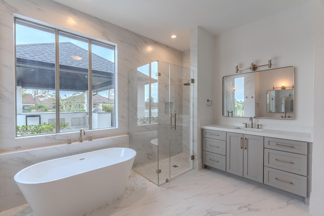 bathroom featuring plus walk in shower, a healthy amount of sunlight, and vanity