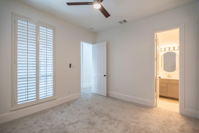 unfurnished bedroom with light carpet, sink, connected bathroom, and ceiling fan