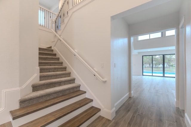 staircase with hardwood / wood-style flooring and a towering ceiling