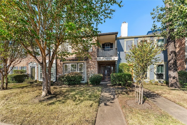 multi unit property featuring a balcony and a front lawn