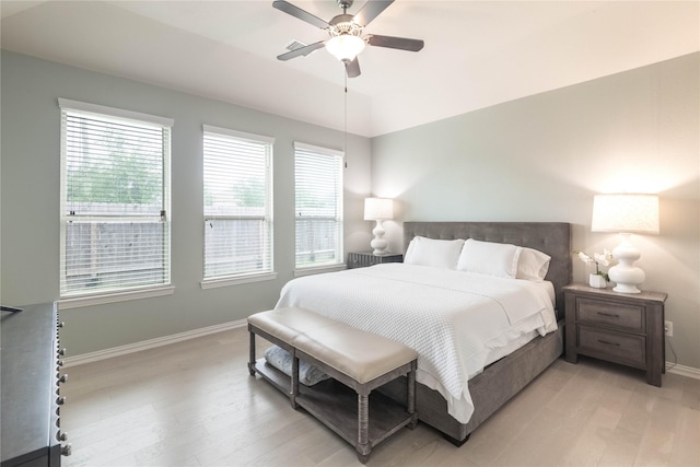 bedroom with light wood-type flooring, ceiling fan, and multiple windows