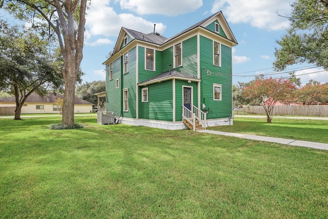 view of front of property with central air condition unit and a front yard