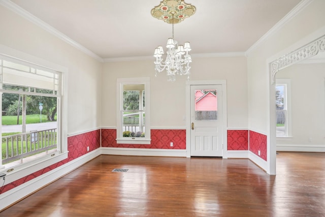 interior space featuring wood-type flooring, crown molding, a notable chandelier, and a healthy amount of sunlight