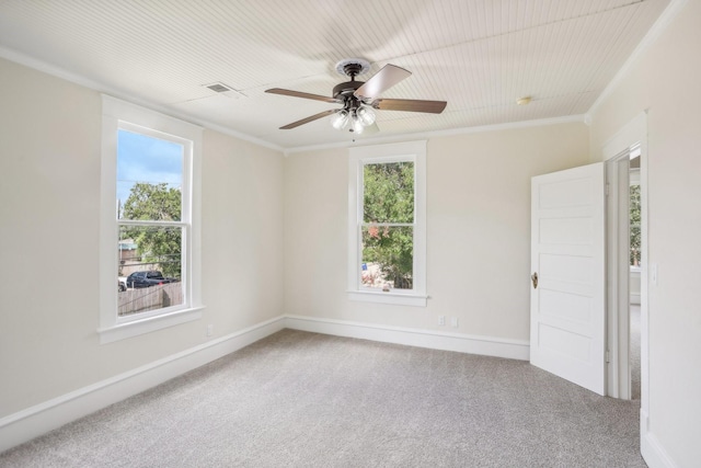 carpeted spare room featuring ceiling fan, crown molding, and plenty of natural light