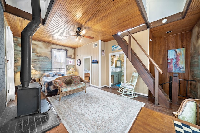 bedroom with wood-type flooring, wooden ceiling, wood walls, and a wood stove