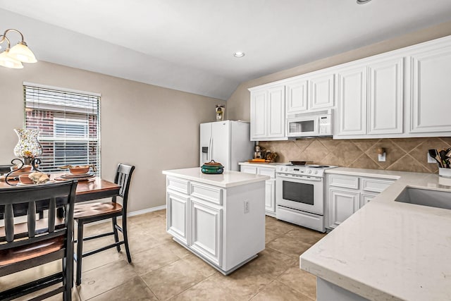 kitchen featuring white appliances, white cabinets, a center island, and lofted ceiling