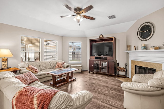 living room featuring hardwood / wood-style flooring, ceiling fan, and a tile fireplace