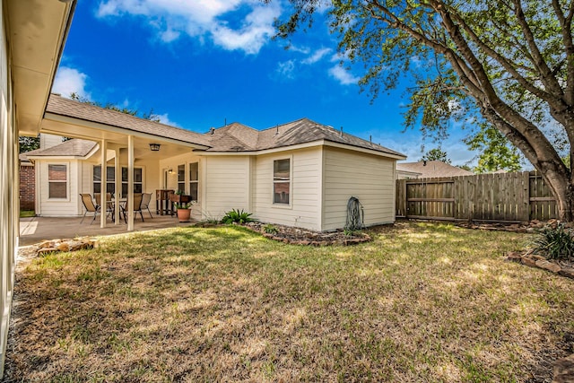 back of house with a patio area and a yard