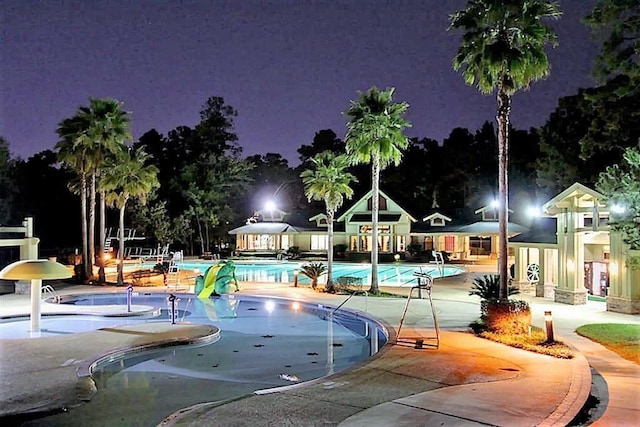 pool at night featuring a patio