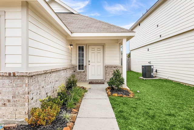 entrance to property with cooling unit and a lawn