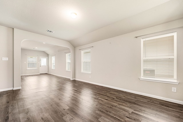 spare room with dark wood-type flooring and lofted ceiling