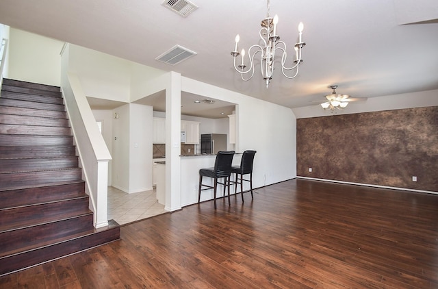 interior space featuring ceiling fan with notable chandelier and light wood-type flooring