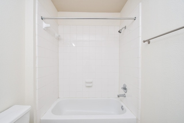 bathroom featuring toilet and tiled shower / bath