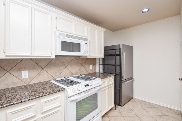 kitchen with white cabinetry, white appliances, and dark stone countertops