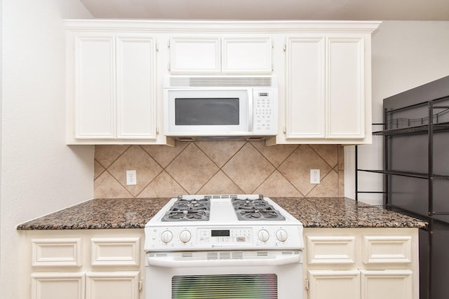 kitchen with backsplash, white appliances, and dark stone counters