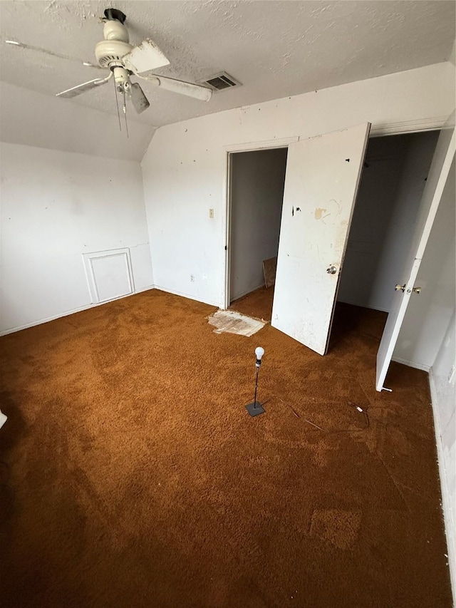 interior space with ceiling fan, a textured ceiling, dark colored carpet, and vaulted ceiling