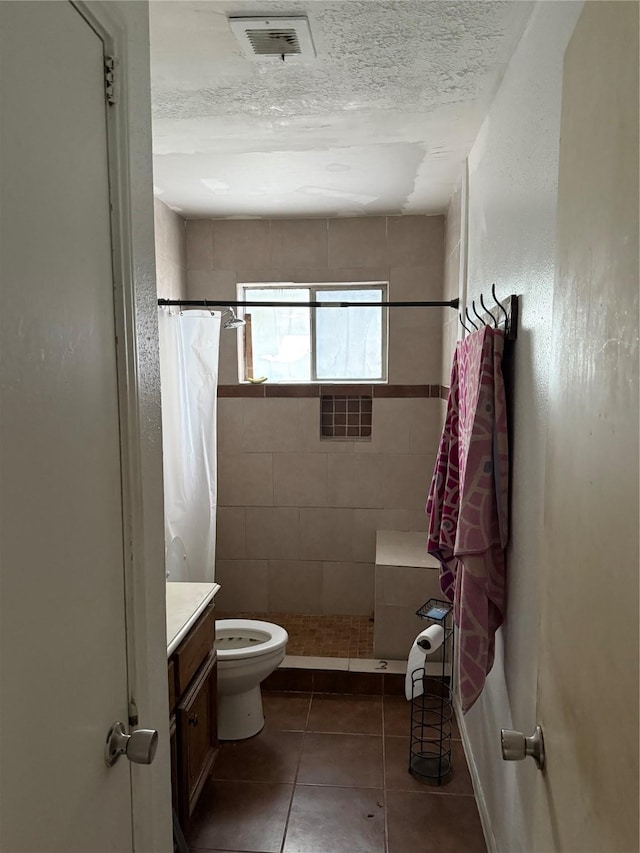 bathroom with a textured ceiling, walk in shower, vanity, and toilet