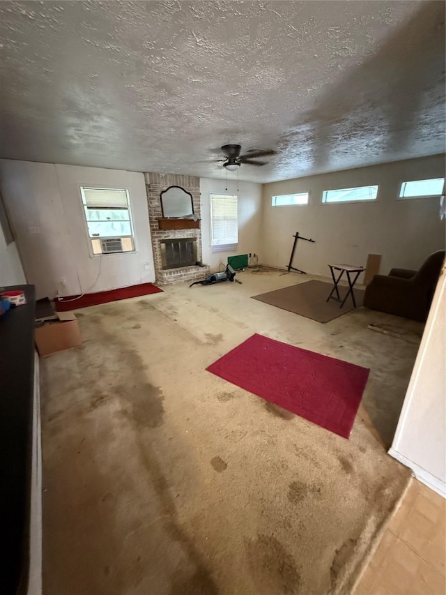 interior space with ceiling fan, a brick fireplace, a textured ceiling, and cooling unit