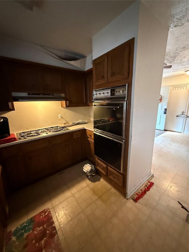 kitchen with dark brown cabinetry, stainless steel gas cooktop, and multiple ovens