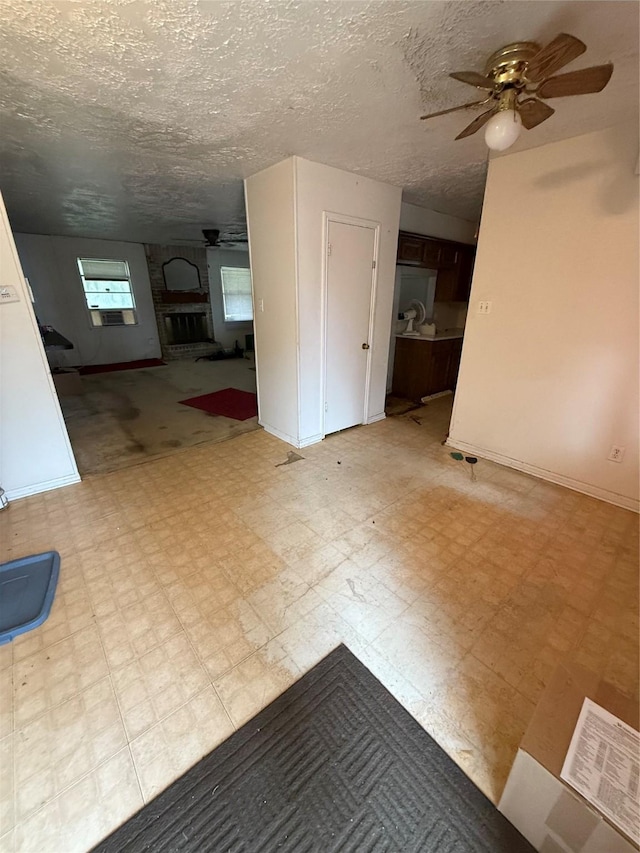 interior space featuring a large fireplace, ceiling fan, and a textured ceiling