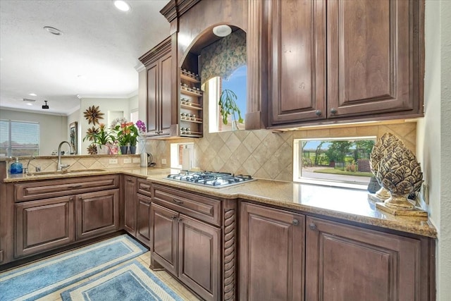 kitchen with stainless steel gas cooktop, tasteful backsplash, sink, kitchen peninsula, and light stone counters