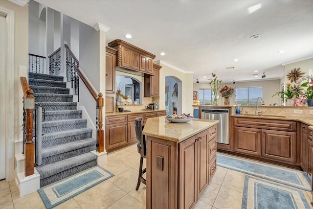 kitchen featuring a kitchen island, sink, ornamental molding, a breakfast bar, and stainless steel dishwasher