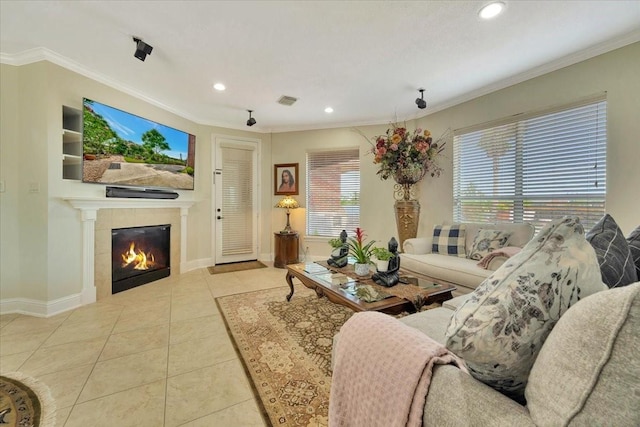 living room with crown molding, a tiled fireplace, and light tile patterned flooring