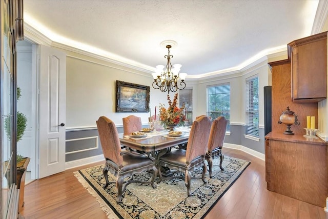 dining room featuring hardwood / wood-style flooring, ornamental molding, and an inviting chandelier