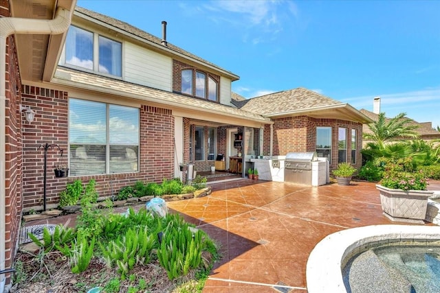 back of property featuring a patio and an outdoor kitchen