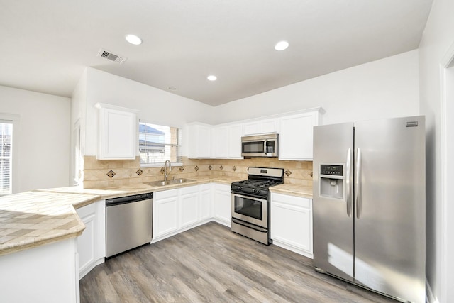 kitchen with white cabinetry, appliances with stainless steel finishes, sink, and backsplash