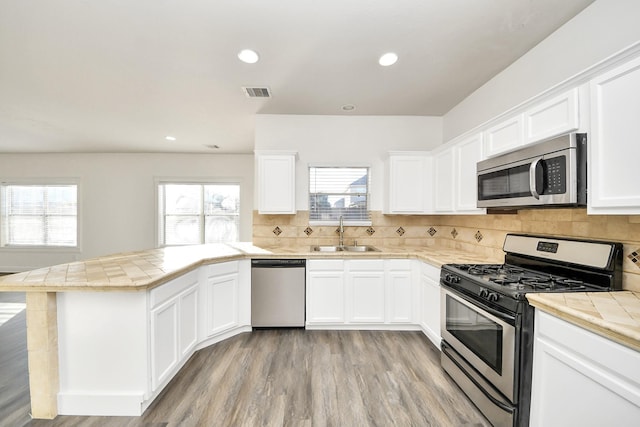 kitchen featuring white cabinetry, appliances with stainless steel finishes, sink, and tile countertops