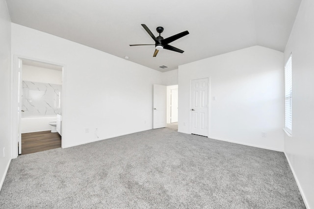 unfurnished bedroom featuring ensuite bathroom, lofted ceiling, carpet floors, a closet, and ceiling fan