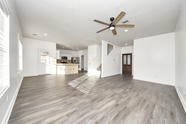 unfurnished living room with ceiling fan, a wealth of natural light, and light hardwood / wood-style floors