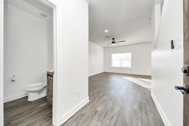 interior space with vanity, ceiling fan, wood-type flooring, and toilet