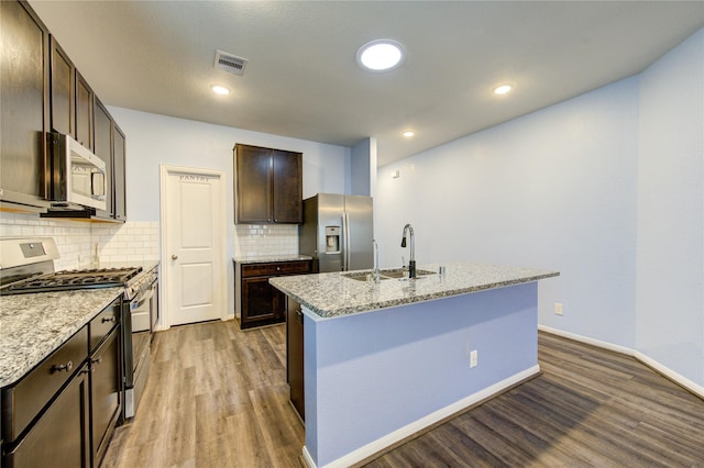 kitchen featuring dark brown cabinetry, stainless steel appliances, a kitchen island with sink, and sink